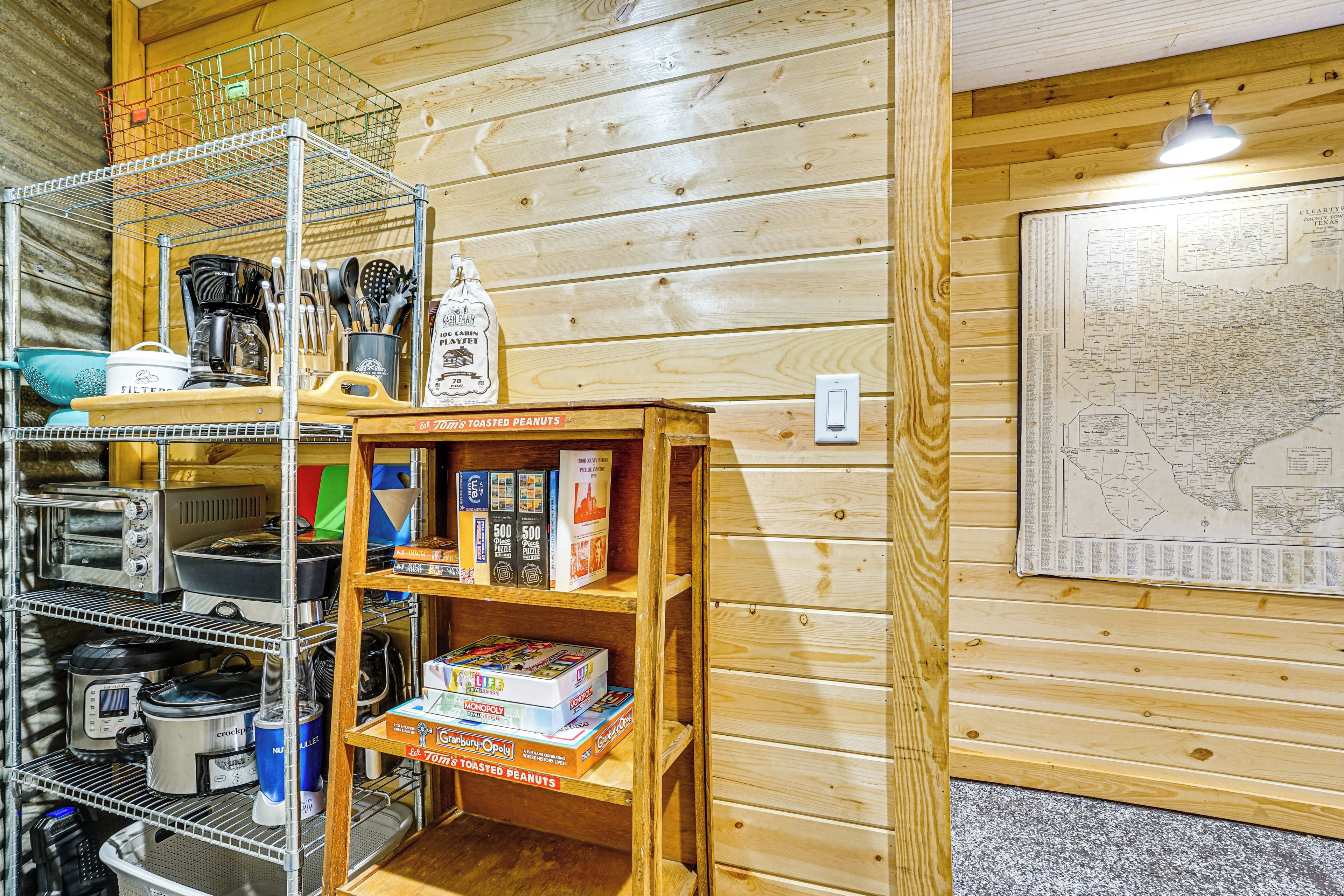 A kitchen with wooden walls, a map, and shelves with kitchenware and board games.
