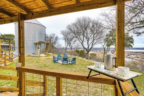 Eine Holzterrasse mit Blick auf ein Silo, Sitzgelegenheiten im Freien und ein Couchtisch mit Tassen und einem Wasserkocher.