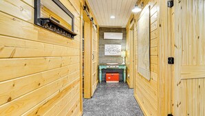 A narrow hallway with wooden walls and a tiled floor, leading to a room with a sign that reads "Tin de Blue Bath House." - Tin De Blue Grainbury Silo and Cabins (Weatherford)