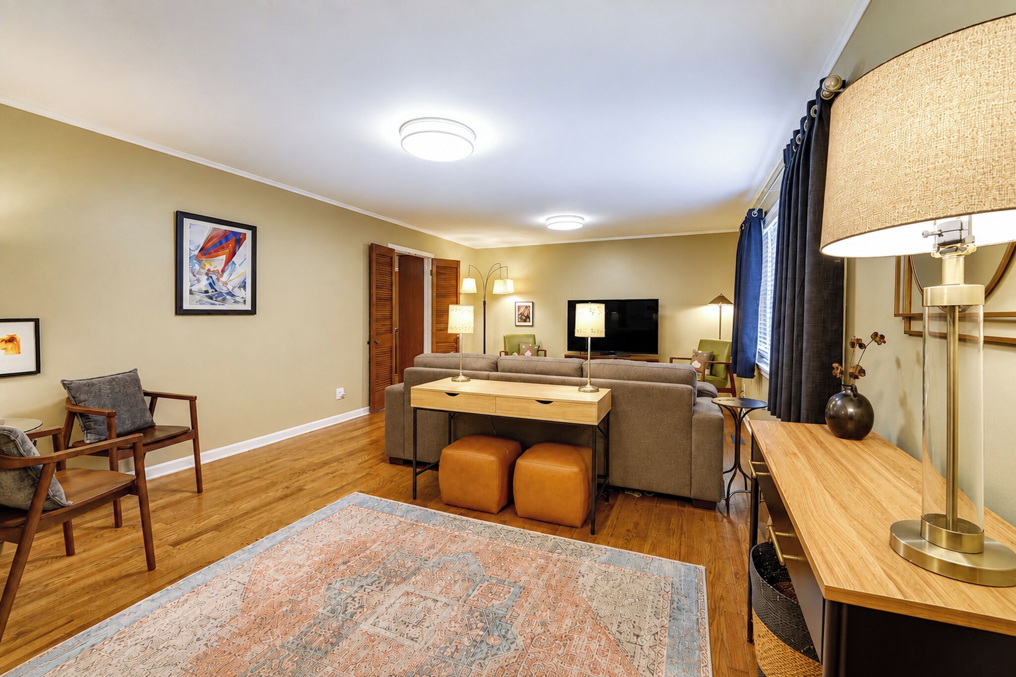 Un salon moderne comprenant un canapé, des poufs, une table basse, un téléviseur et une lampe.