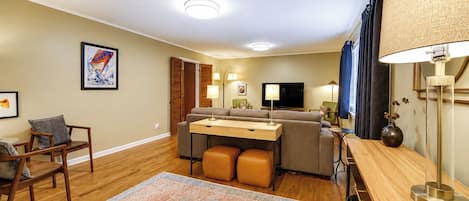 A modern living room with a sofa, ottomans, a coffee table, a TV, and a lamp.
