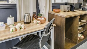 Une cuisine avec un plan de travail en bois, une chaise noire, un four à micro-ondes, un grille-pain et divers ustensiles de cuisine.