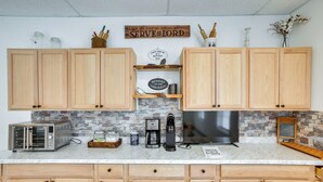 A kitchen with wooden cabinets, a toaster, a coffee maker, and a refrigerator.