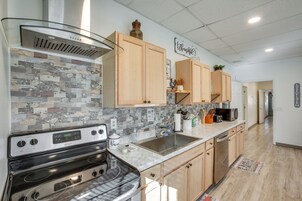 Una cocina moderna con campana extractora de acero inoxidable, armarios de madera, salpicadero de azulejos y encimera de mármol.