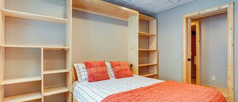 Un dormitorio con cama, estanterías empotradas y una puerta a otra habitación.