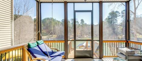 A covered porch with a swing chair, a cushioned bench, and a table.