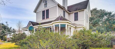 A two-story house with a wrap-around porch, a chimney, and a well-maintained lawn.