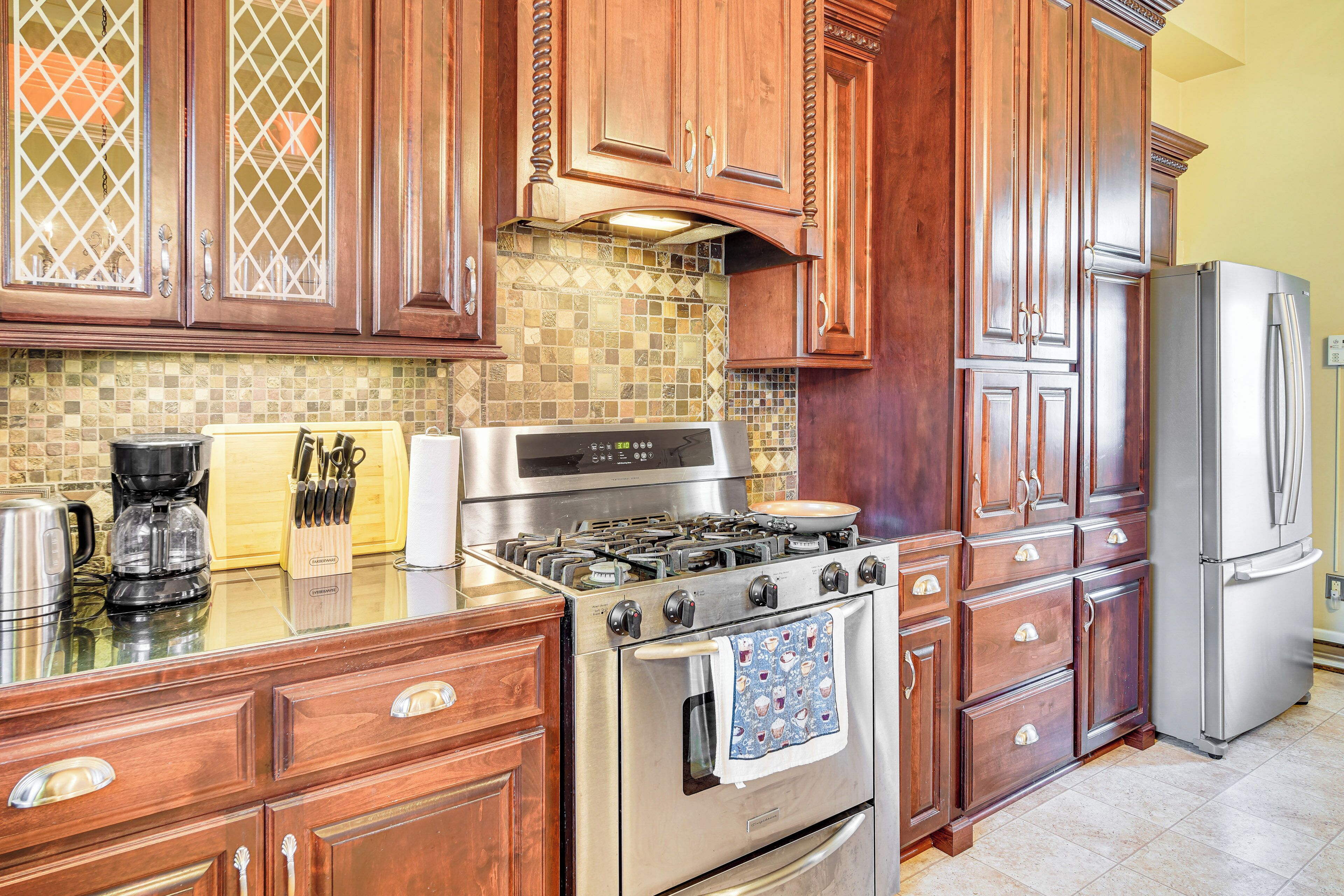 A kitchen with wooden cabinets, a stainless steel stove, and a refrigerator.
