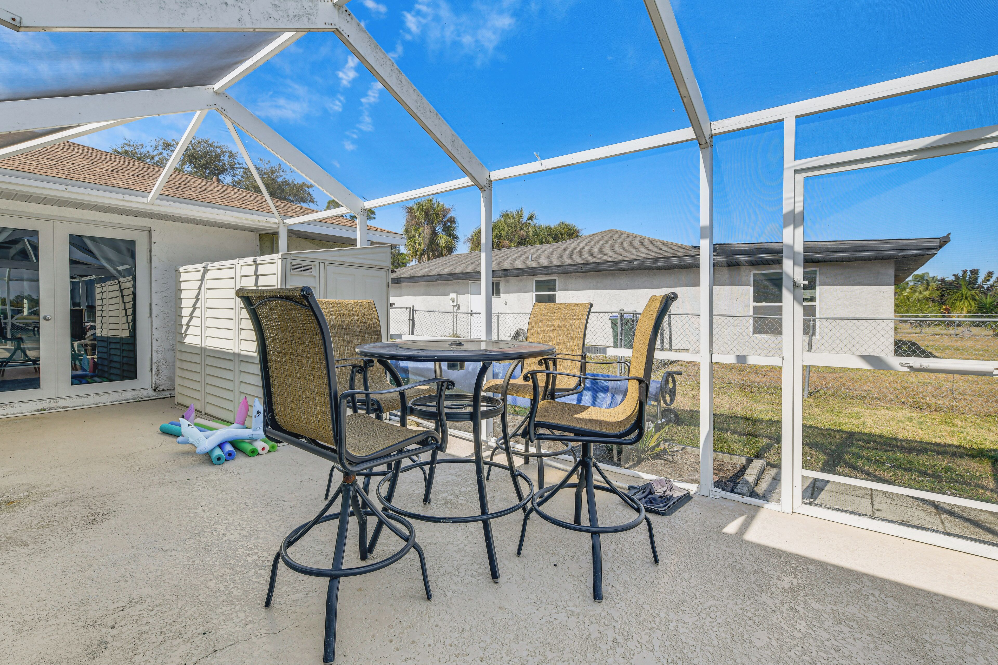 A covered patio with a table and chairs, a sliding glass door, and a view of a residential area.