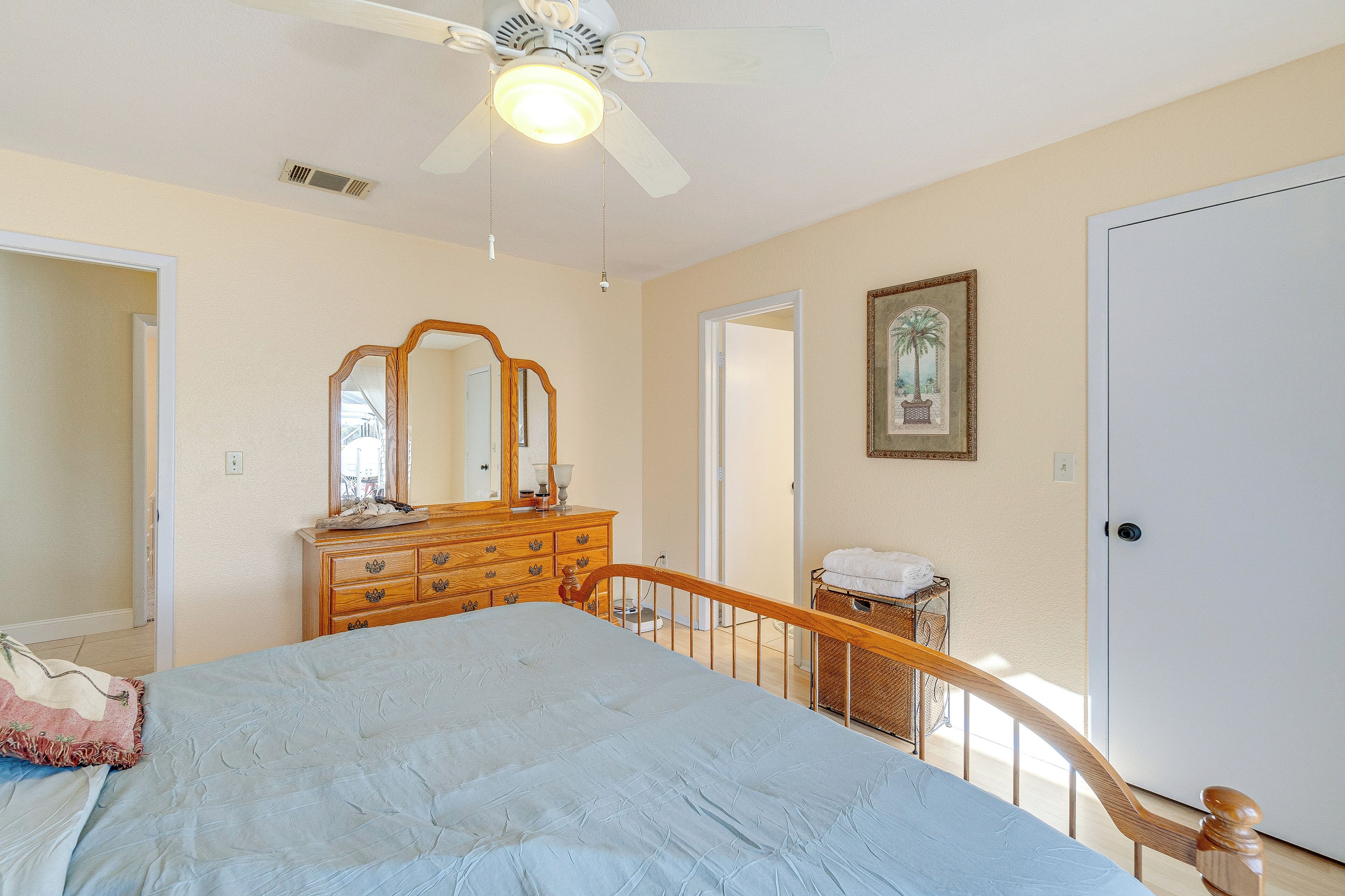 A bedroom with a bed, dresser, and a ceiling fan.
