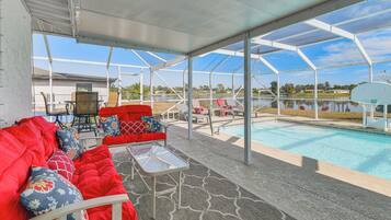 A covered outdoor area with a pool, red seating, and a view of the surrounding landscape.