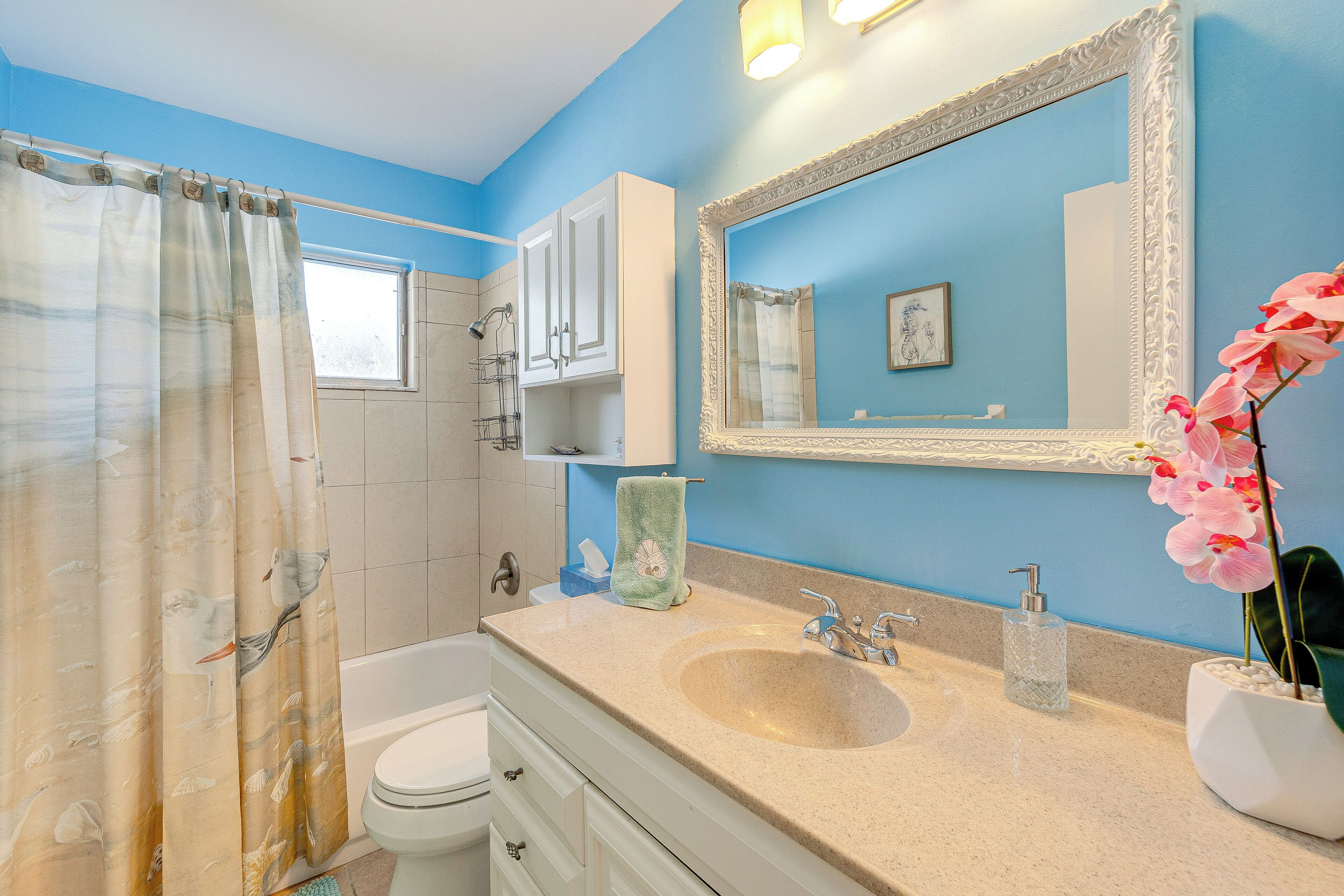 A bathroom with a bathtub, a sink, a mirror, and a toilet.