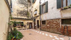 A courtyard with a checkered floor, potted plants, and a hose on the right. - Ca Nova II by Wonderful Italy (Venecia)