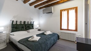 A bedroom with a bed, a nightstand, an air conditioning unit, a window, and a radiator. - Ca Nova II by Wonderful Italy (Venecia)
