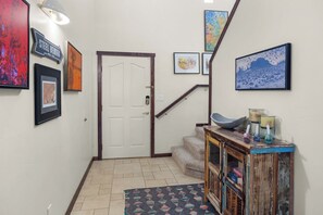 A hallway with a white door, a staircase, and a wooden console table with candles and decorative items.