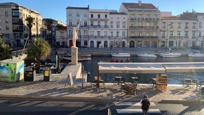 Une promenade en bord de mer bordée d’immeubles, avec une statue et des bateaux amarrés.