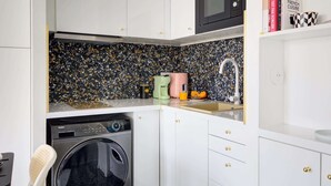 A compact kitchen with a washing machine, a microwave, and a sink.