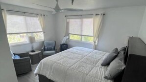 A bedroom with a bed, two bedside tables, a chair, and a wardrobe.