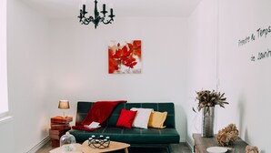 A modern living room with a green sofa, a coffee table, and a bookshelf.
