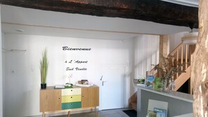 A reception area with a wooden cabinet, a welcome sign, a staircase, and a door.