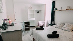 A modern bedroom with a bed, bedside tables, a desk, and a wardrobe.