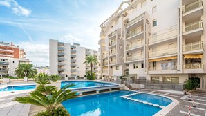 Un hôtel moderne doté d’une piscine centrale, de nombreux balcons et d’un espace extérieur bien entretenu agrémenté de palmiers.