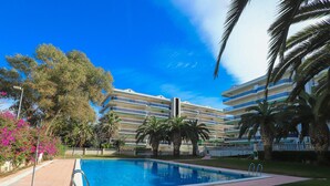 Un hôtel doté d’une piscine, de palmiers et surplombant un ciel bleu azur.