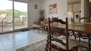 Un espace repas comprenant une grande table, des chaises et donnant sur un balcon avec vue sur la ville.