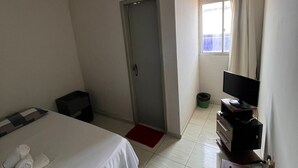A hotel room with a bed, a TV, a desk, and a window with curtains. - Pousada santos  (Barreirinhas)