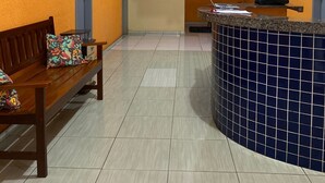 A reception area with a reception desk, a bench with colorful cushions, and a painting on the wall. - Pousada santos  (Barreirinhas)