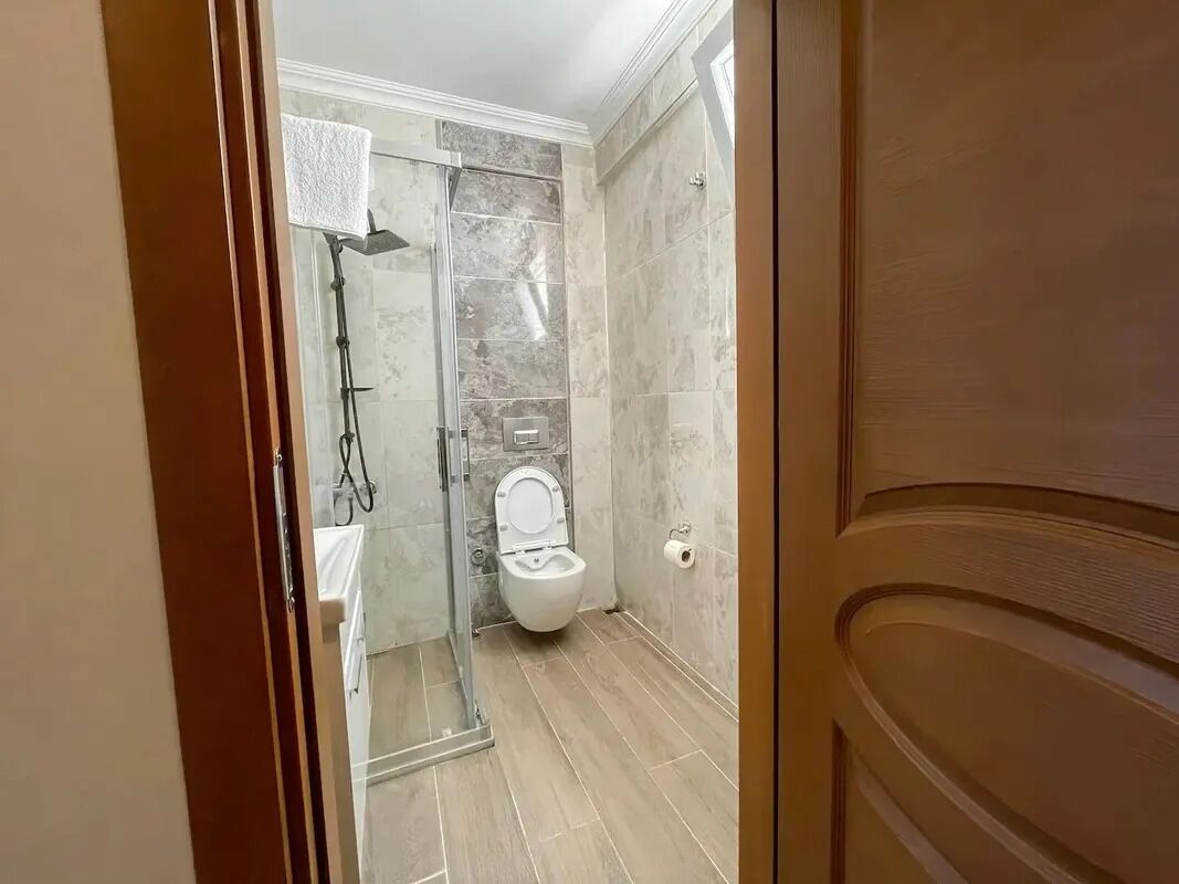 A bathroom with a shower, toilet, and a towel rack.