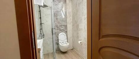 A bathroom with a shower, toilet, and a towel rack.