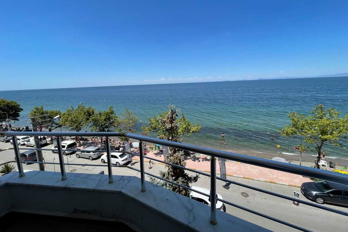 Un balcon donnant sur la mer et sur des voitures garées.