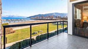A balcony with a view of a lake, mountains, and a dock. - Kids Love Hidden Bunk Room - Seasons at Sandpoint (Sandpoint)