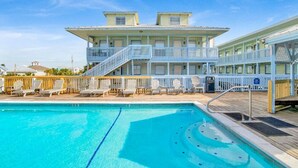 Un hotel con piscina, varios balcones y mobiliario exterior.