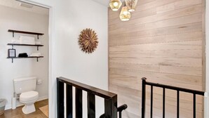 Un baño moderno con una pared de acento de madera, un inodoro blanco y un elemento decorativo en la pared.