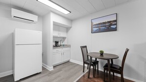 A modern kitchen with white cabinetry, a built-in stove, and a dining area with a table and chairs. - Sc11-silver Cove 11 1 Bedroom Condo (Branson)