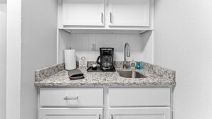 A small kitchenette with white cabinets, a granite countertop, a coffee maker, a sink, and a few toiletries. - Sc11-silver Cove 11 1 Bedroom Condo (Branson)