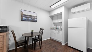 Una cocina moderna con armarios blancos, microondas integrado, una mesa de comedor con sillas y un refrigerador grande.