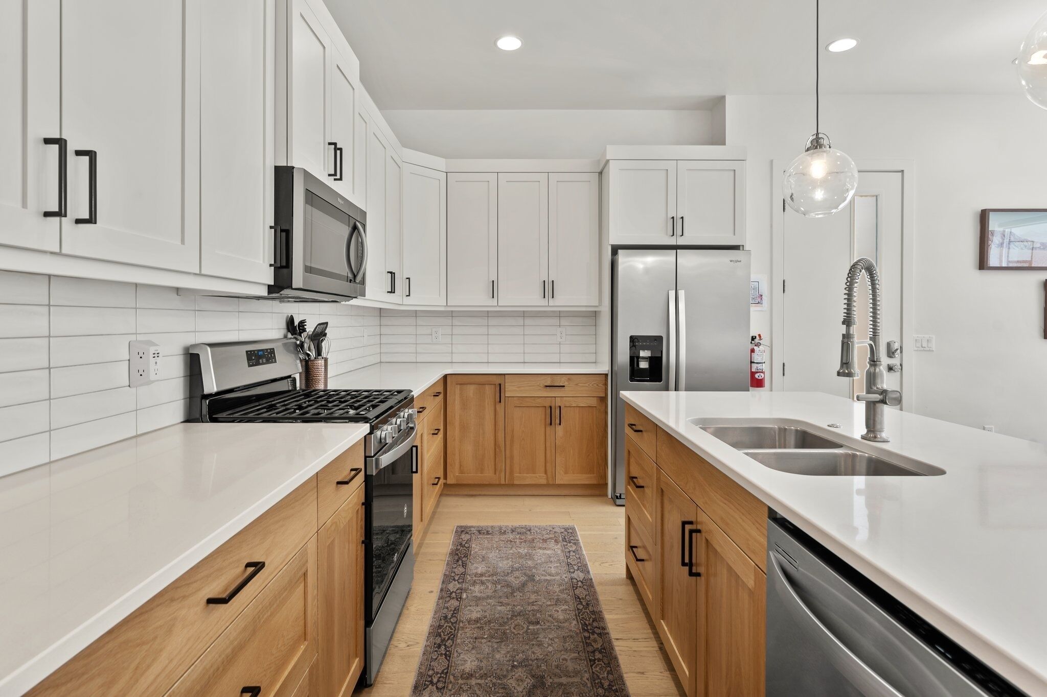 A modern kitchen with white cabinets, stainless steel appliances, and a large island with a sink.