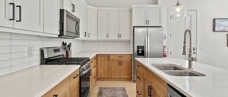 A modern kitchen with white cabinets, stainless steel appliances, and a large island with a sink.