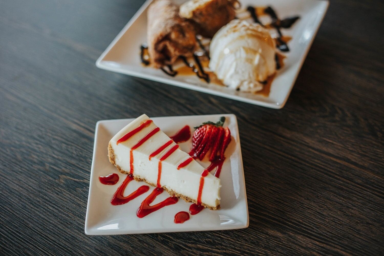A dessert plate with a slice of cheesecake and strawberries on a wooden table.