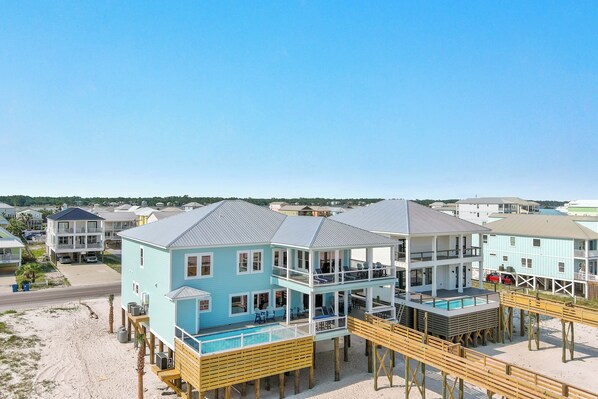 Une propriété située en bord de mer, comprenant plusieurs niveaux, notamment un espace piscine et un coin salon extérieur.