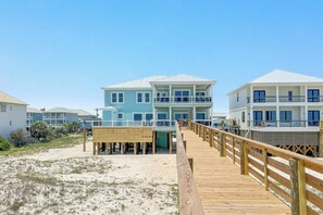 Une propriété située en bord de mer, avec une promenade en bois menant à un immeuble à plusieurs étages doté de balcons.
