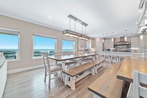 Une cuisine spacieuse dotée d’un grand îlot central, d’appareils électroménagers modernes et de grandes fenêtres offrant une vue sur l’océan.