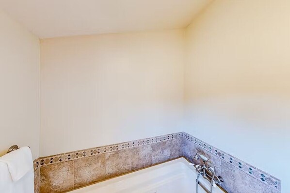 A bathroom with a bathtub, a shower, and a towel rack.
