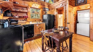 Cocina de cabaña con paredes de madera, una mesa de comedor y un refrigerador.