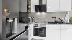 A modern kitchen with a built-in water dispenser, a Bosch oven, and a stainless steel refrigerator. - Modern KüstenHygge 2 with garden & parking space (Westerdeichstrich)