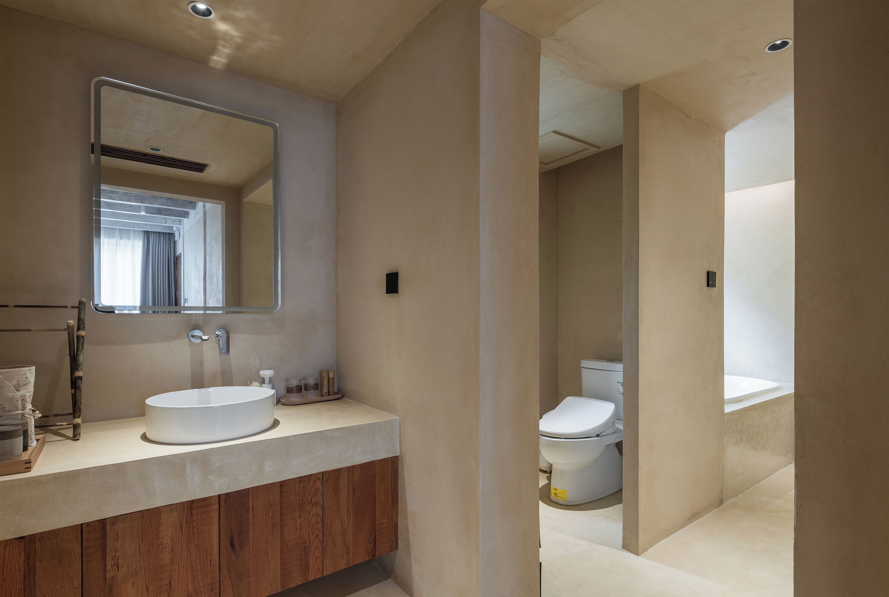 Un baño moderno con tocador de madera, un espejo grande y un inodoro.