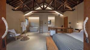A spacious bedroom with a large bed, a wooden desk, a chair, and a bathtub. - Hegu Villa Hotel (Changzhou)